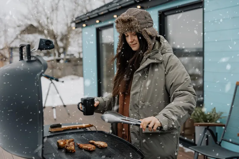 Девушка зимой жарит мясо на мангале